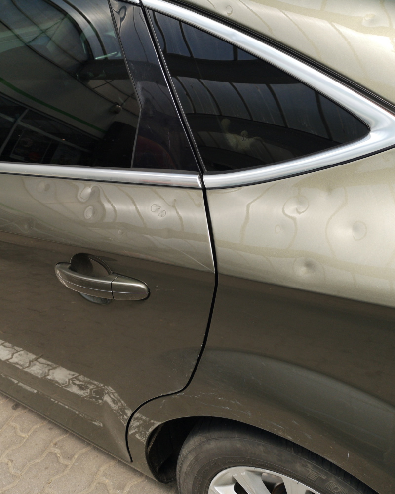 Hail damage along the door panels of a vehicle in a Dallas-Fort Worth paintless dent repair shop