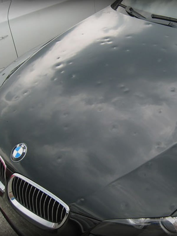 Hail dents across a vehicle hood photographed under shop lighting in Dallas-Fort Worth
