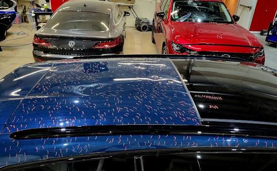 Hail dents marked across a vehicle roof panel during a hail damage assessment