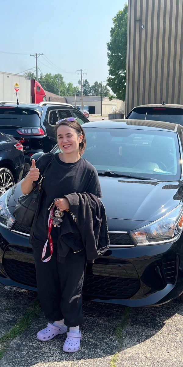 Happy DFW Paintless Dent Repair customer giving a thumbs up next to her black car after a DFW door ding repair