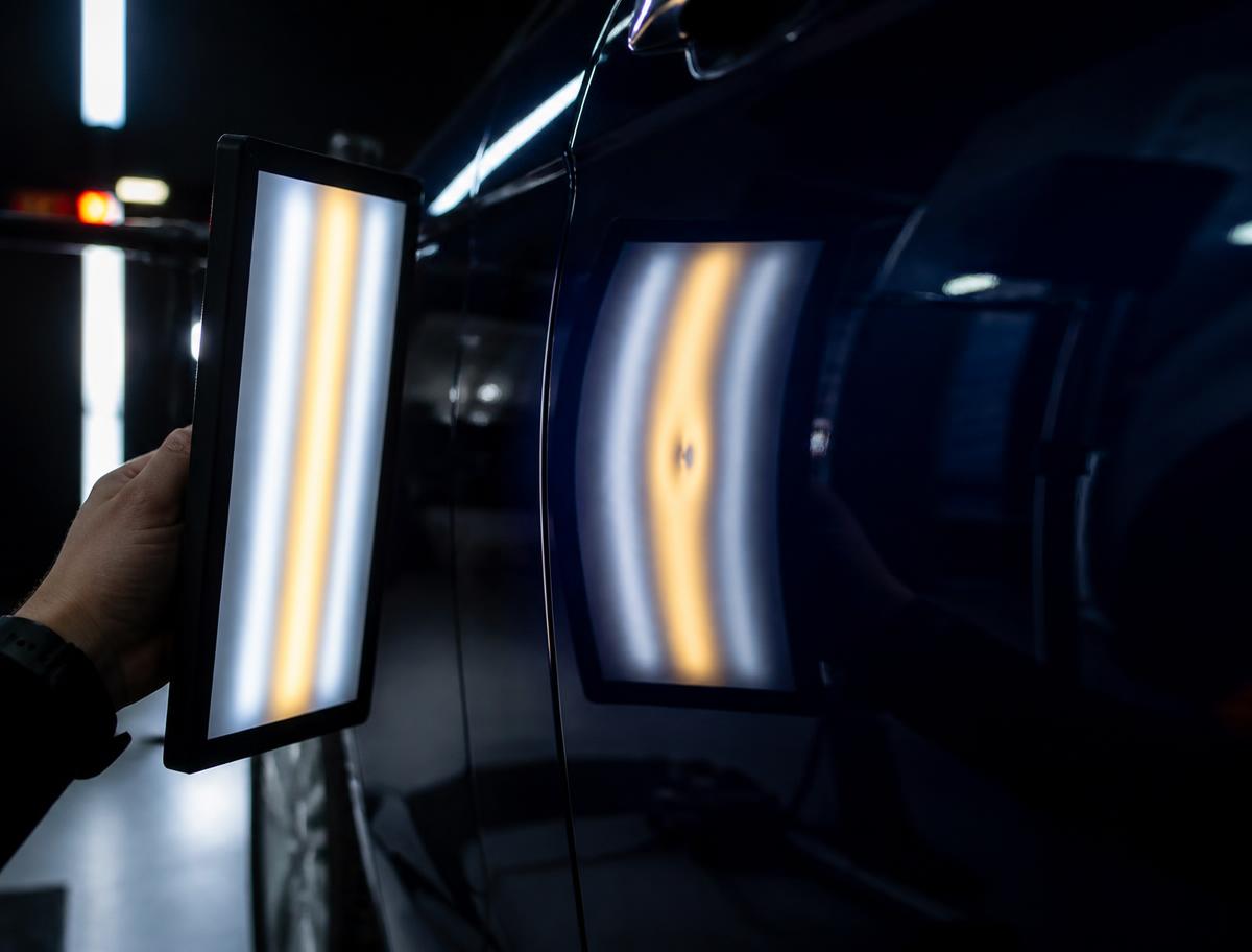 Technician inspecting a panel for collision damage